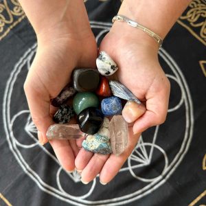 person holding an assortment of tumbled stones and crystal points